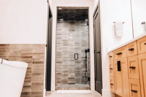 Walk-in shower with glazed tile, glass enclosure, and modern black fixtures.