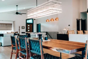 Dining room with wood table, upholstered chairs, and modern rectangular chandelier