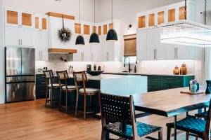 White & green kitchen with oversized island, pendant lighting, custom cabinetry, and open-concept layout.